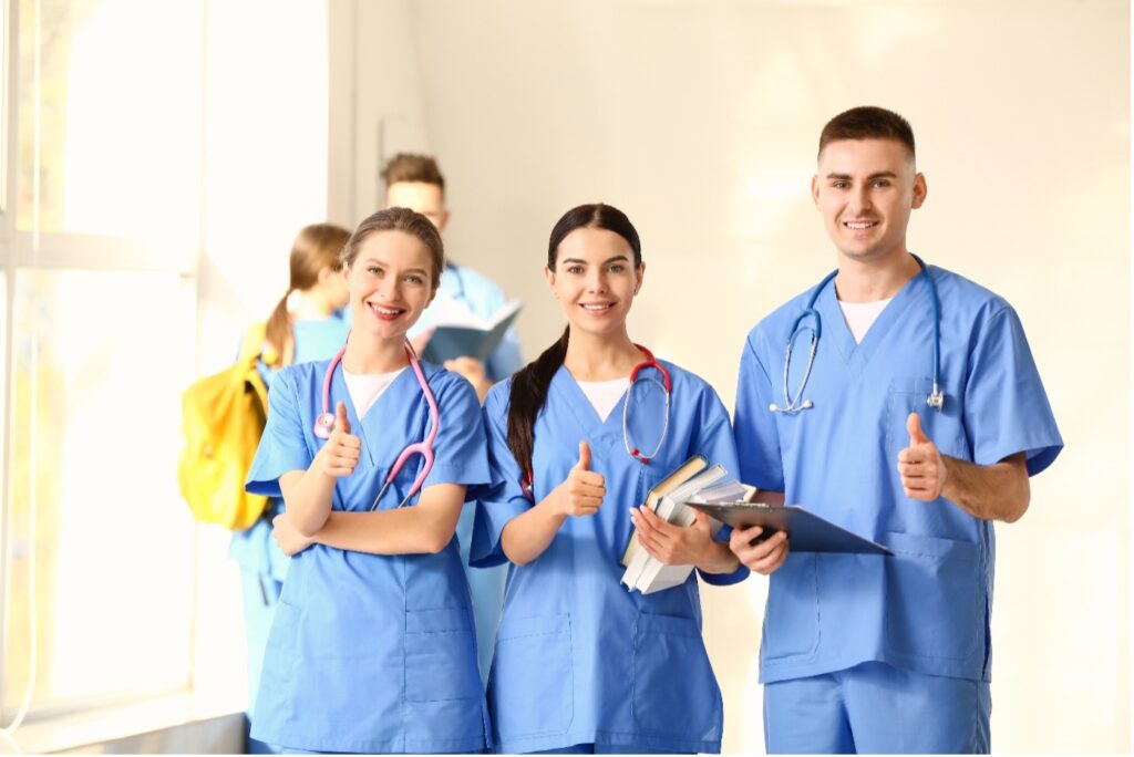 Gruppe von Medizinstudierenden, die in der Klinikhalle eine Daumen-nach-oben-Geste zeigen